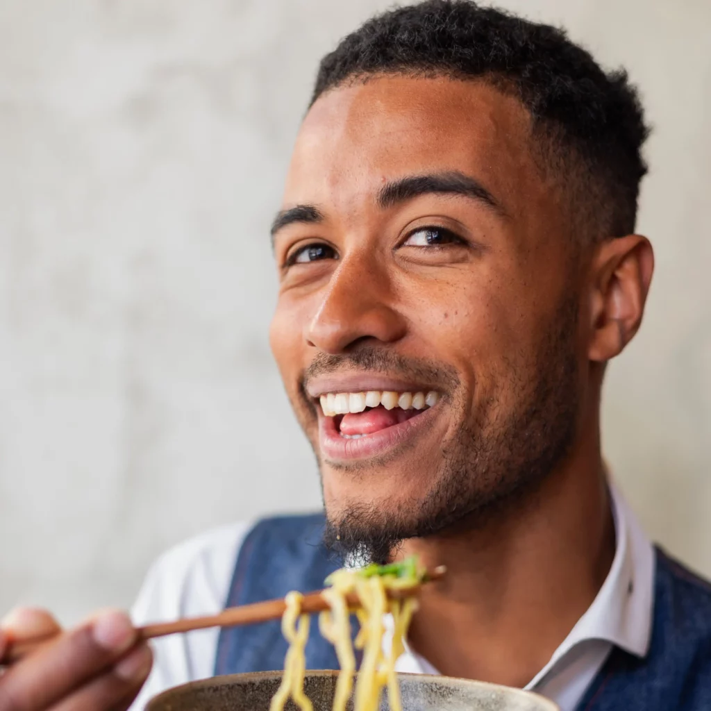 portrait Franck mangeant ramens en souriant